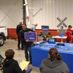 Students watching a man present with a train set up on a table.