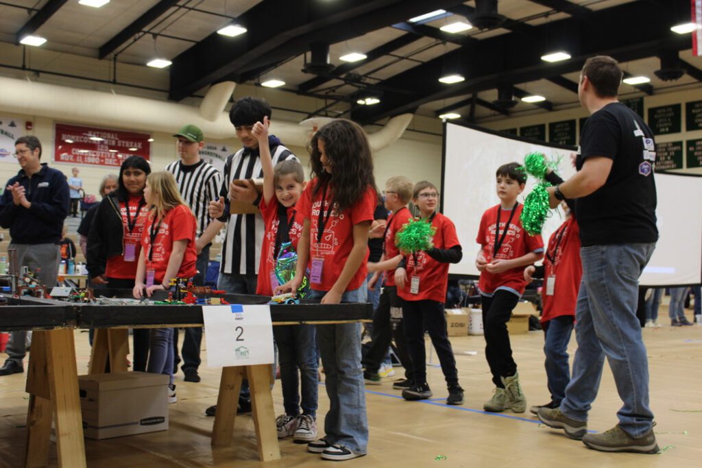 Group photo of students and referees during a robotics match.