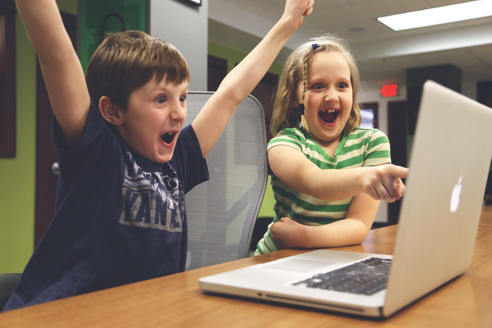 Students smiling brightly at computer screen