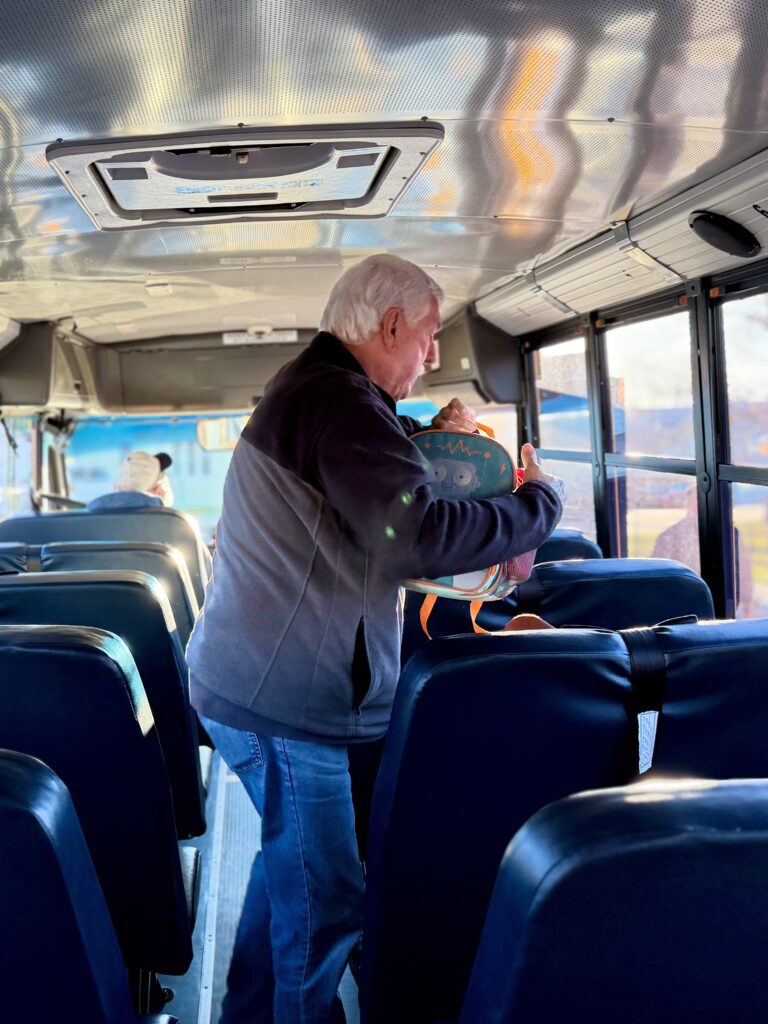 Mr. George assists a student with their backpack, noting that he spoils them.