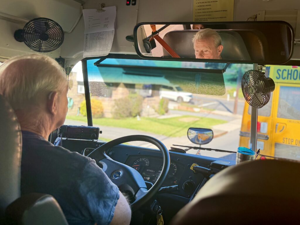 A school bus driver sits in traffic behind another school bus.