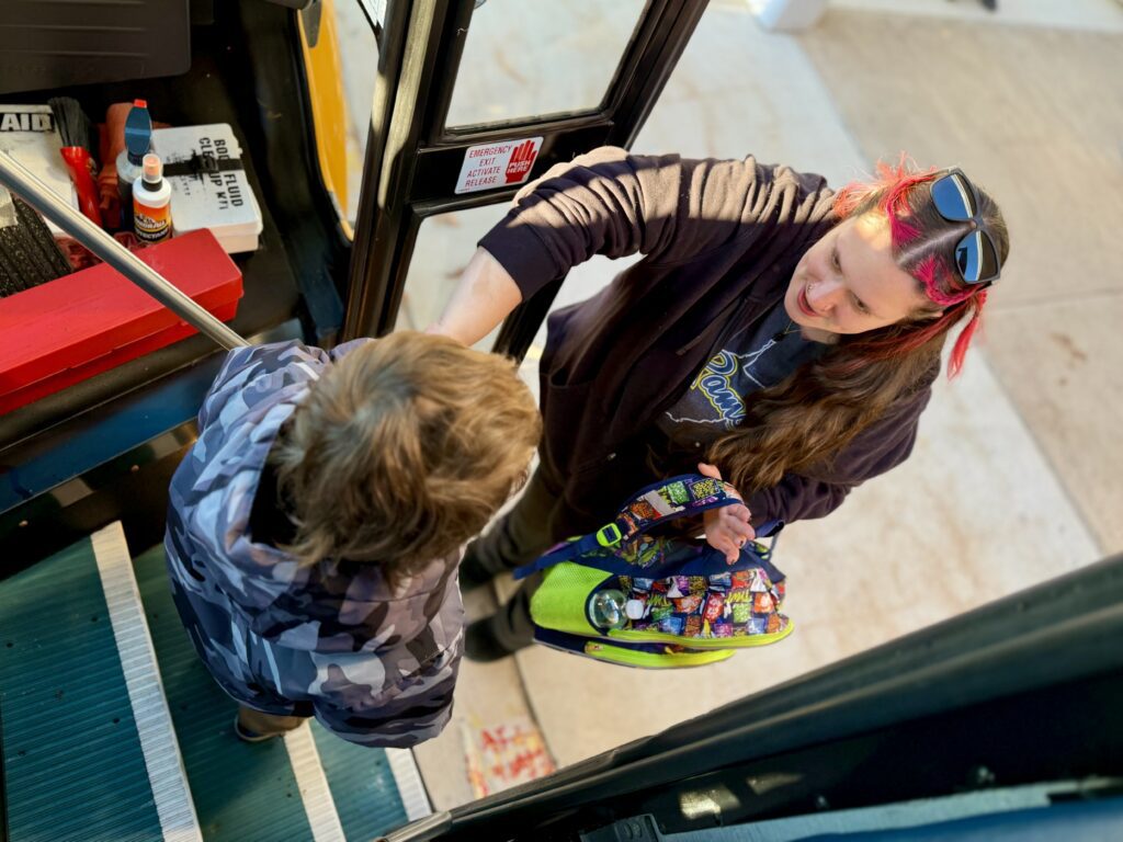 A student exits the bus with the help of a staff member at one of the schools.