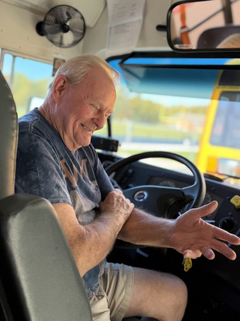 Mr. Tom enjoys a joke while waiting for students.
