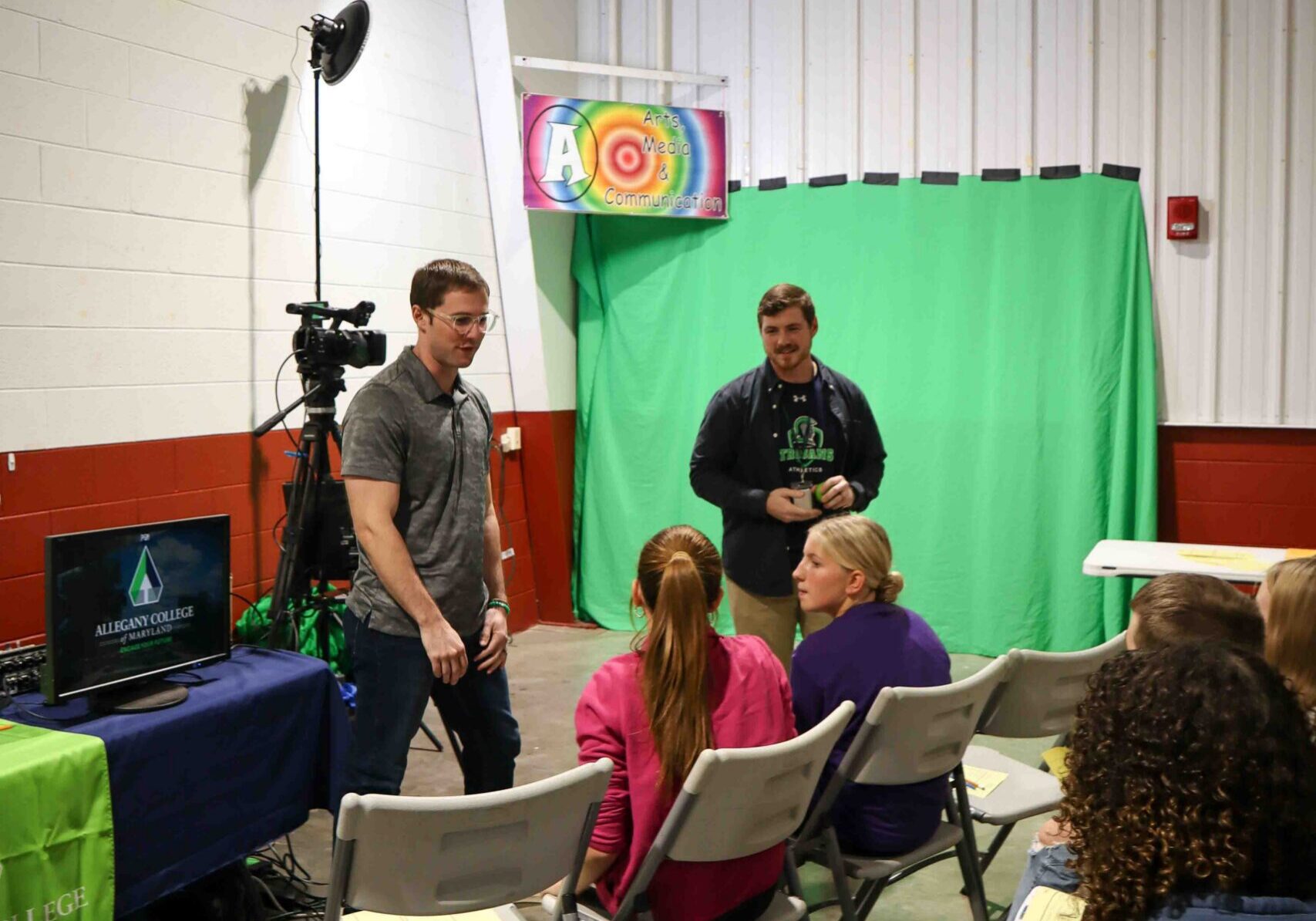 Two men presenting on graphics, audio/visuals to a group of kids.