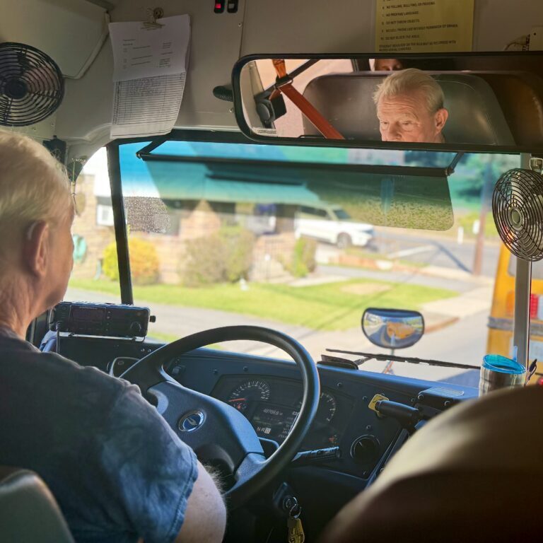 A school bus driver sits in traffic behind another school bus.
